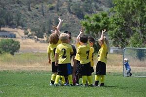 Kids In A Team Huddle With Their Soccer Coach On The Field