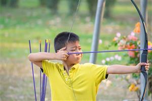 Boy practicing archery at camp