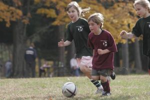 Kids Chasing Soccer Ball Down Field